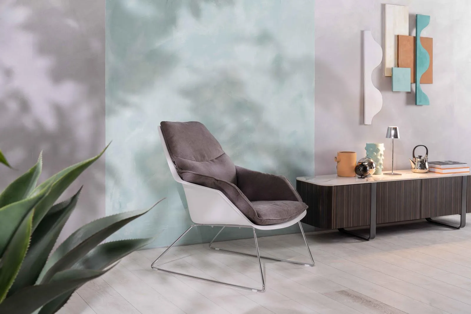Poltrona Grace Stones grigio scuro con base a slitta in un ambiente con mobile basso